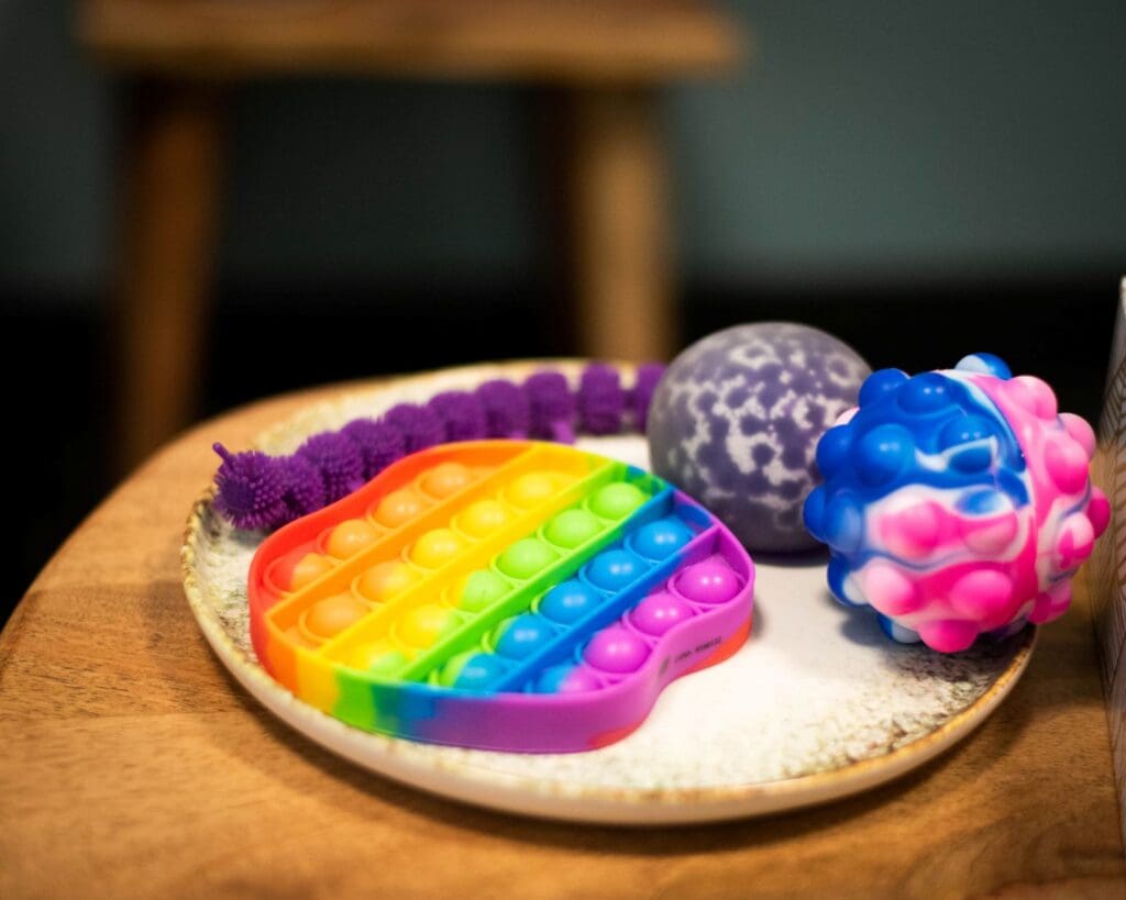 Selection of colourful sensory toys on a plate placed on a table. 